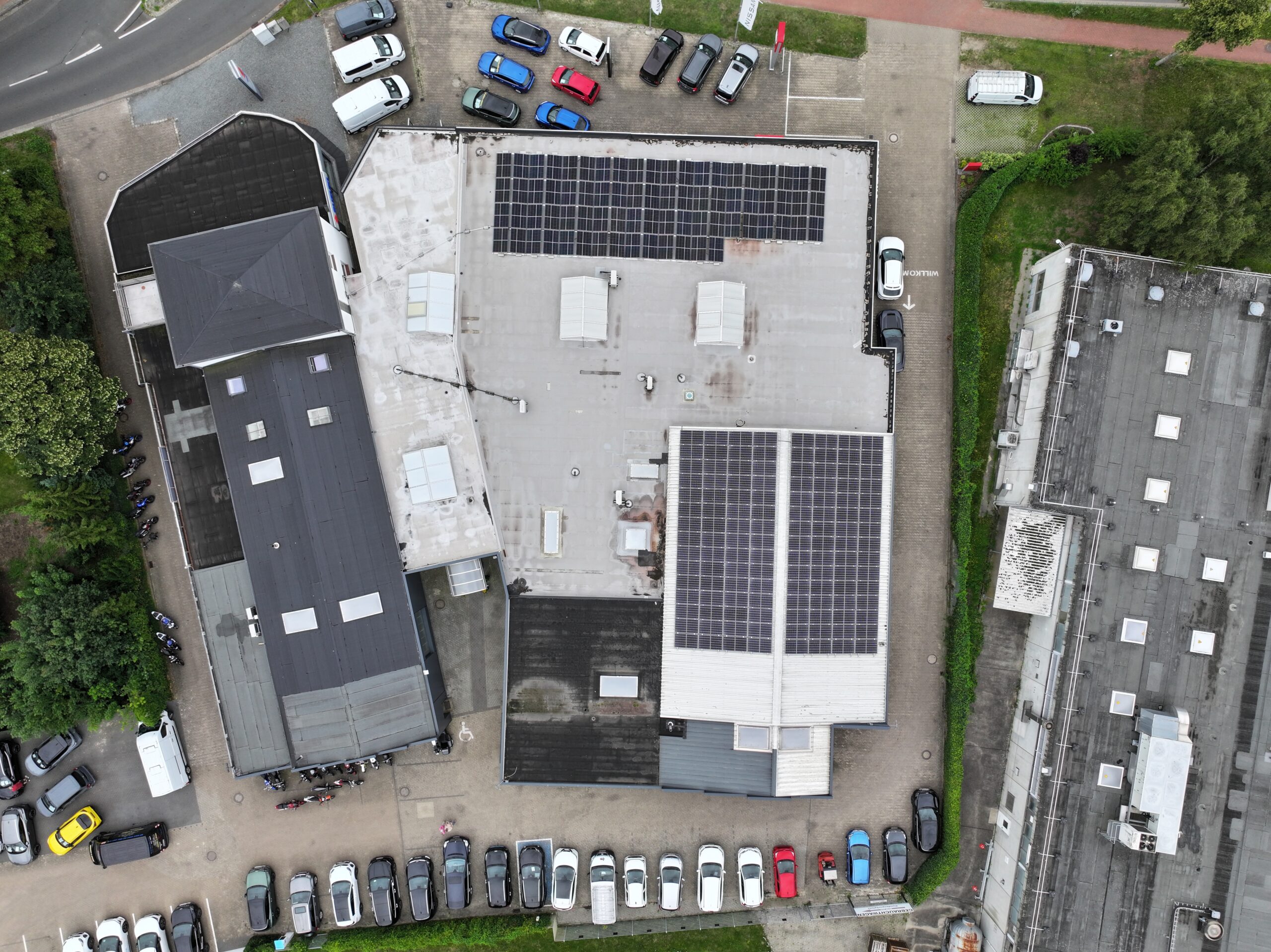 Drohnenaufnahme des Autohaus Hakelberg mit mehreren Gebäuden, Parkplätzen und großen Solaranlagen auf den Dächern.