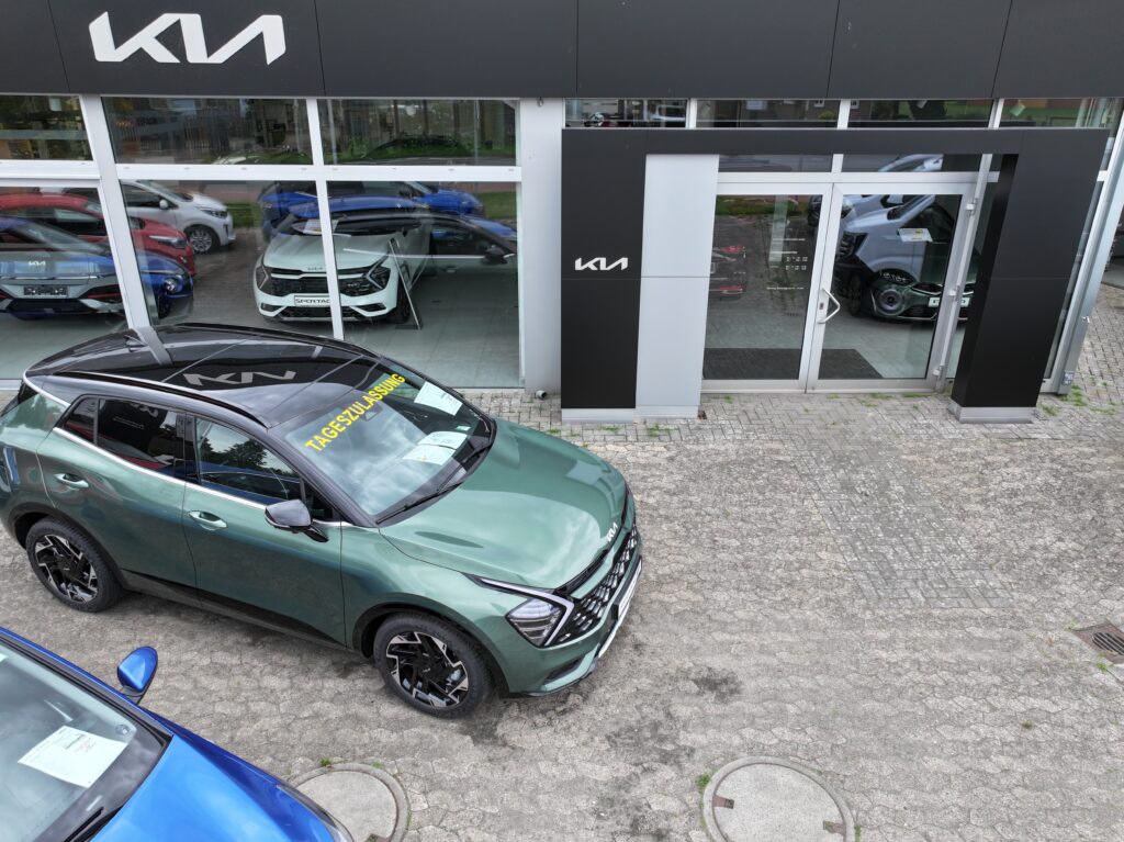 Ein grüner Kia mit dem schriftzug Tageszulassung steht vor dem KIA Showroom