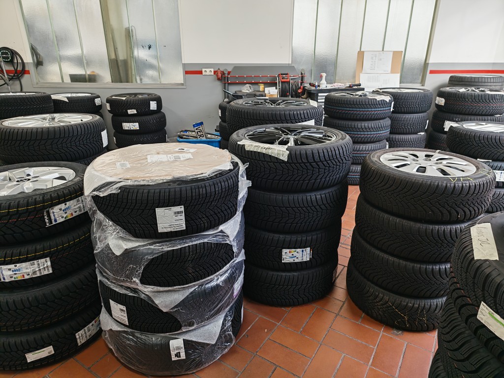 Gestapelte Autoreifen mit Felgen in einer Werkstatt, bereit zur Montage oder Einlagerung.