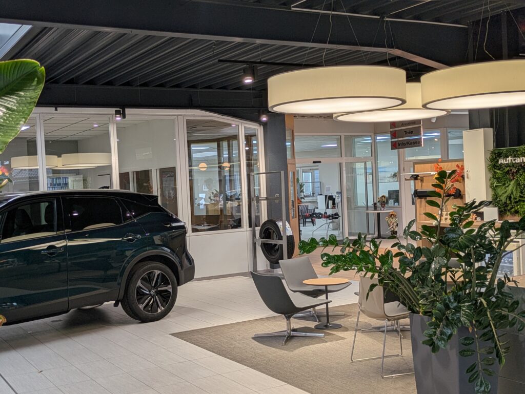 Heller KIA-Ausstellungsraum mit modernem Wartebereich, Pflanzen und ausgestelltem Fahrzeug.