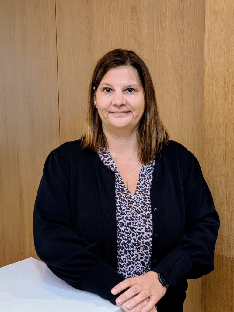 Mitarbeiter im KIA-Servicebereich steht lächelnd an einem weißen Tresen vor Holzrückwand.