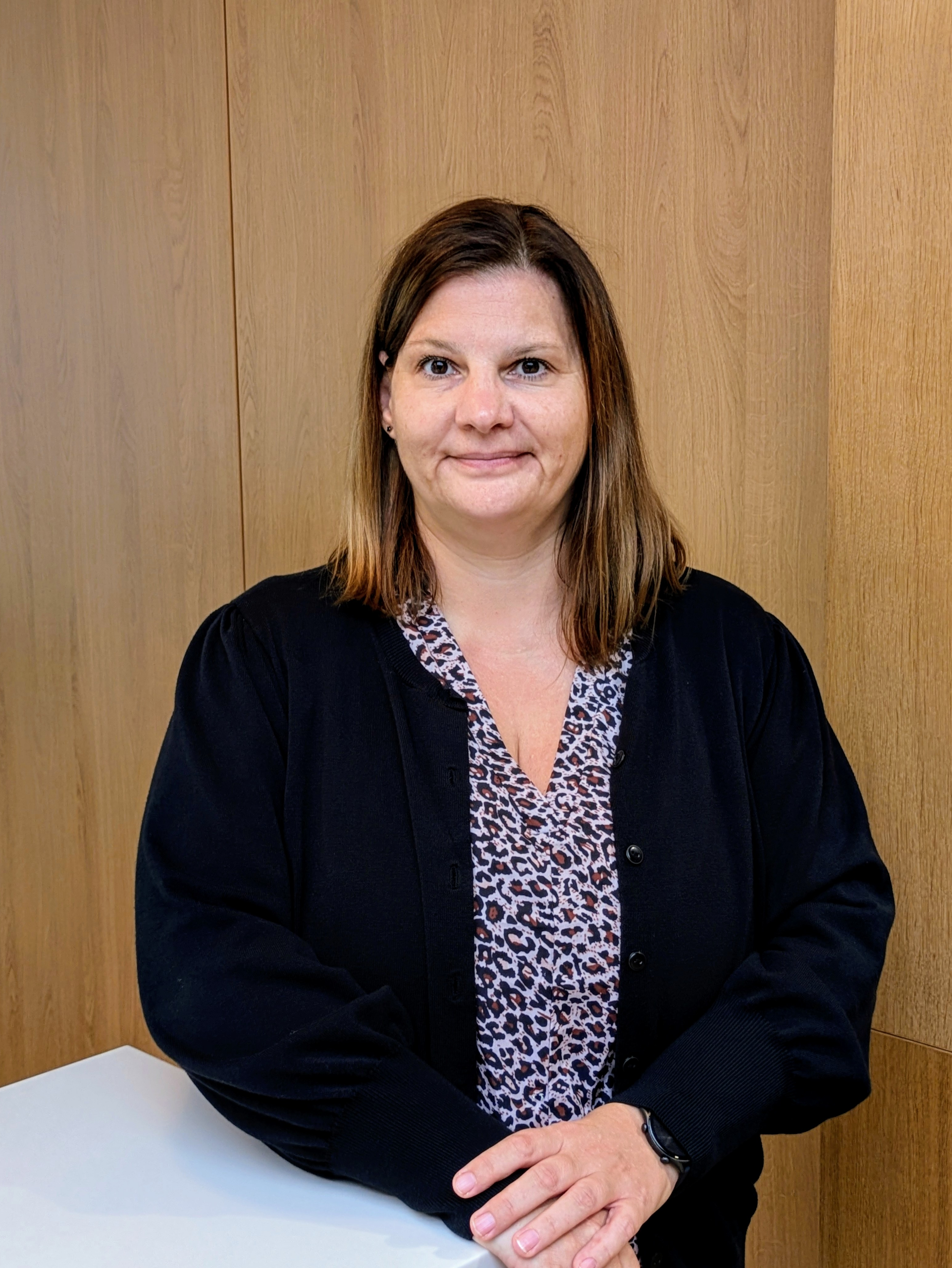 Mitarbeiter im KIA-Servicebereich steht lächelnd an einem weißen Tresen vor Holzrückwand.